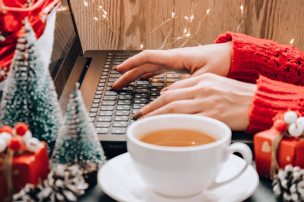 Christmas online shopping, work and education. New Year decorations on table. Woman with notebook